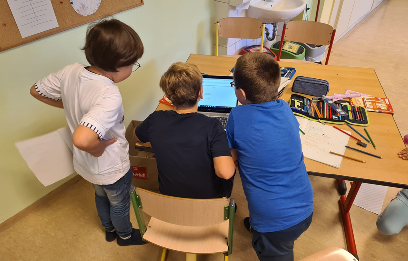 Drei Kinder vor einem Laptop