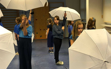 Kinder halten für ein Kunstprojekt Regenschirme in die Höhe.