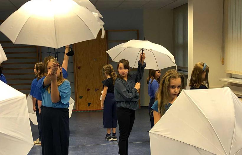 Kinder beim Theaterprojekt mit weißen Regenschirmen