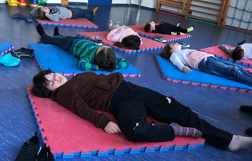 Kinder auf Matten liegend bei Entspannungsübungen