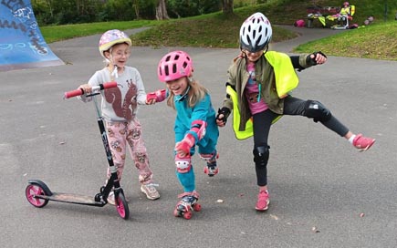 Drei Kinder mit Helmen auf Skaterbahn