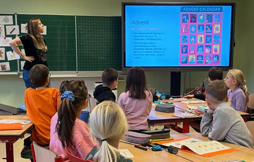 Kinder vor einer digitalen Tafel mit Lehrerin